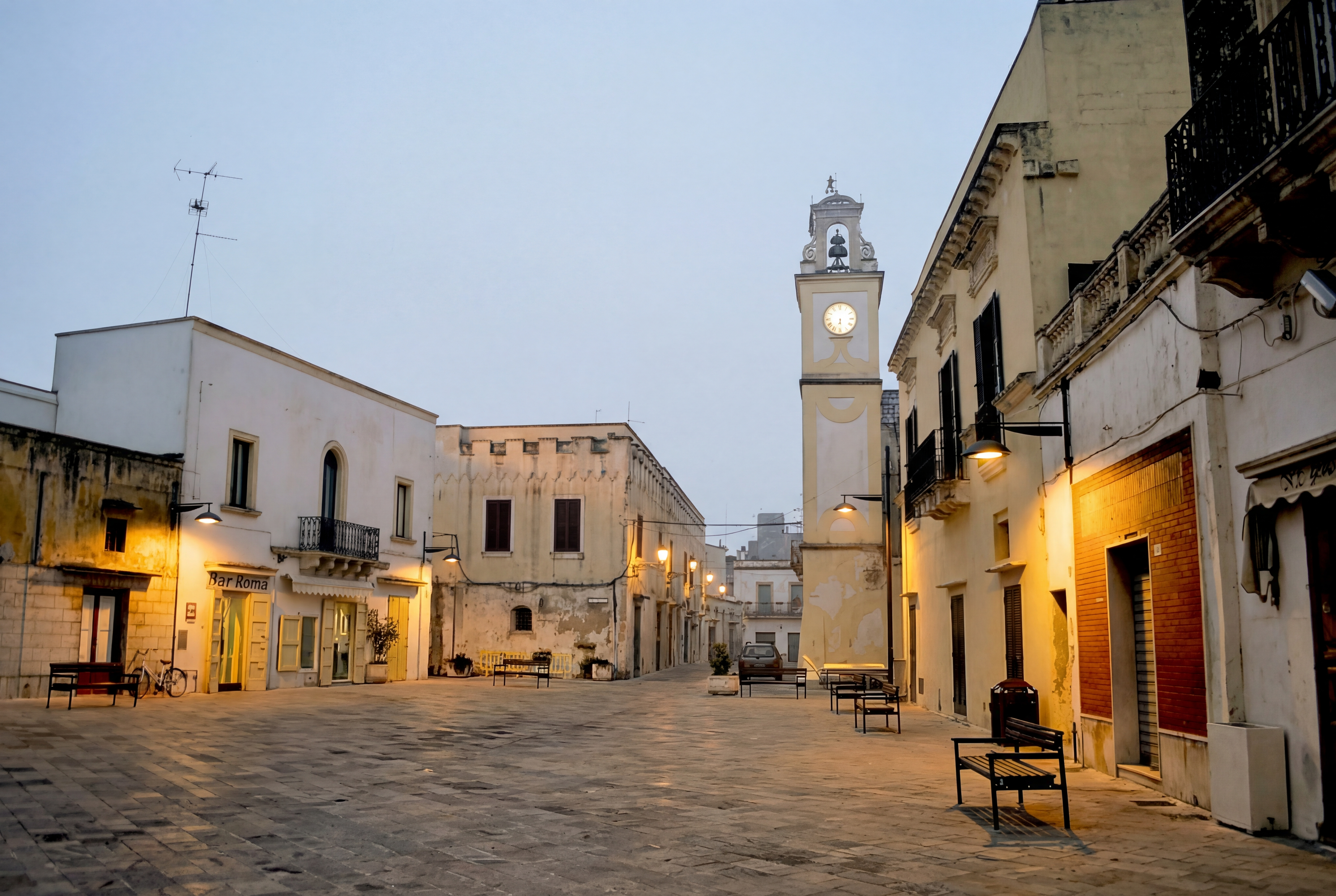 Historic Salento piazza at dusk with clock tower and warm streetlights near Porto Cesareo