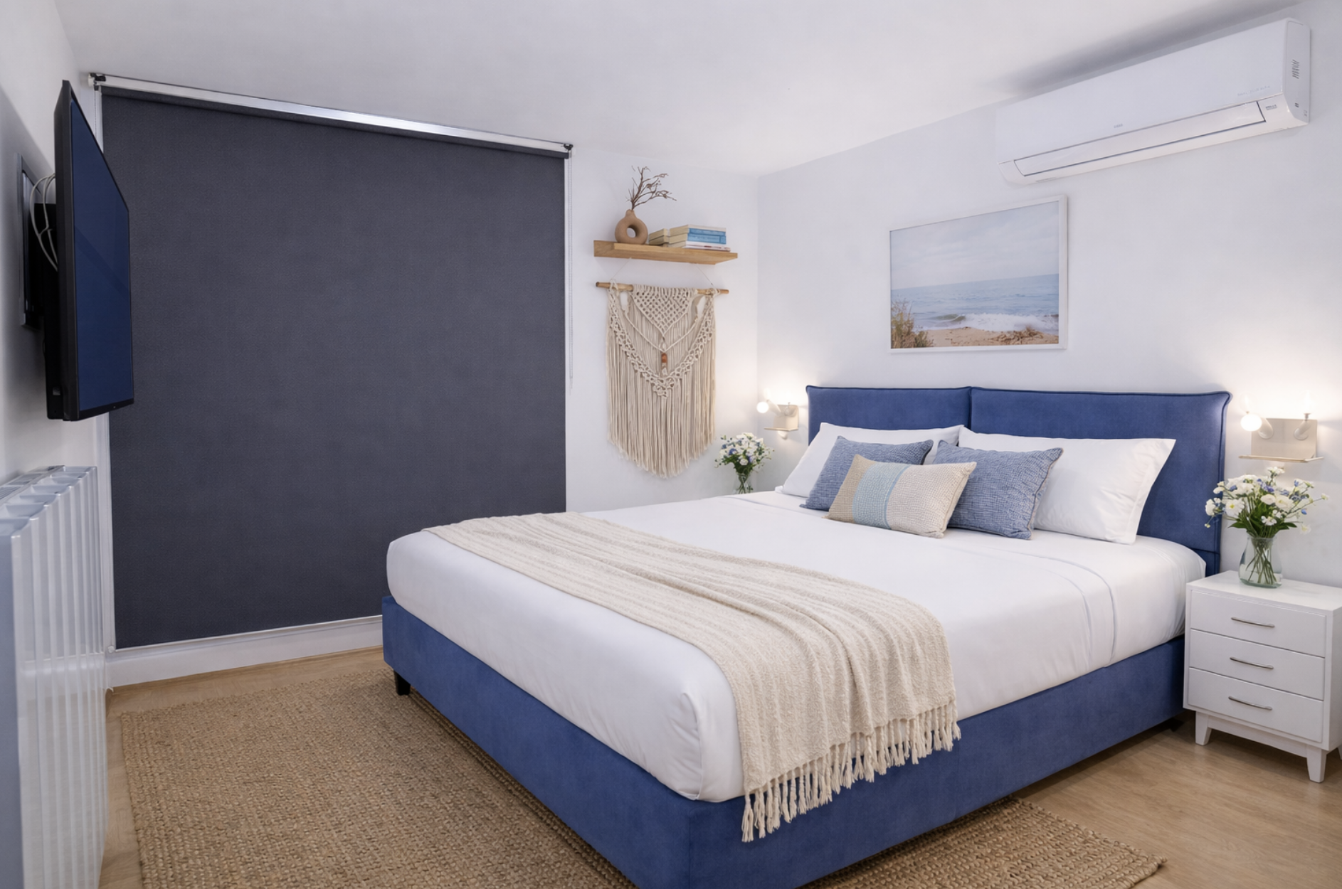 Upper level bedroom with blue queen bed, macramé wall art, and sea painting in Sunset Garden Mare, Porto Cesareo