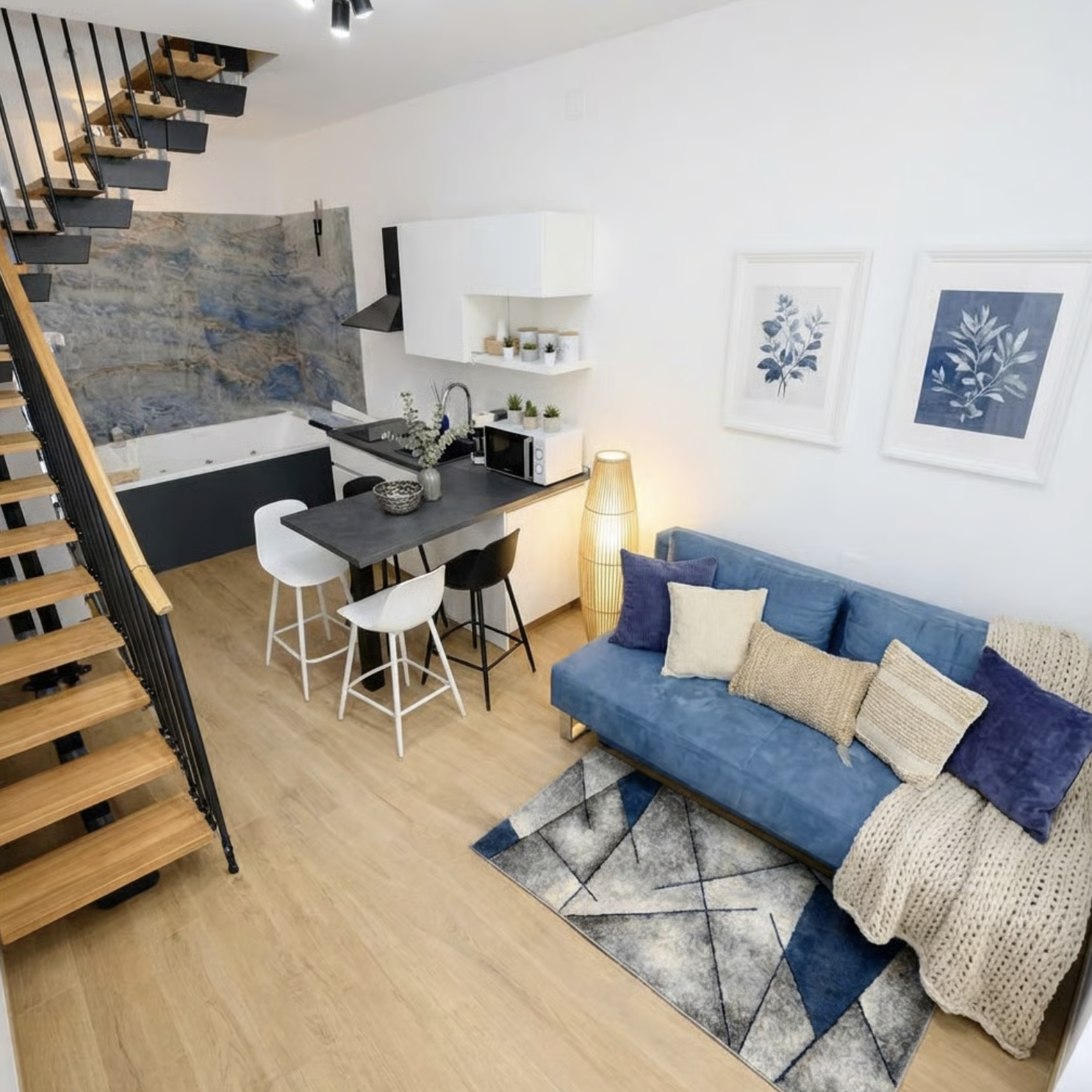 Open-plan living area with blue sofa, kitchen island, and staircase to upper level in Sunset Garden Mare, Porto Cesareo