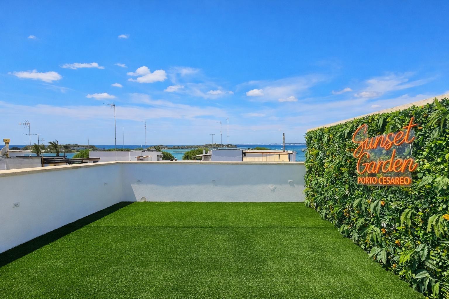 Mare's 40m² private terrace with branded green wall, sea view, and Ionian coastline in Porto Cesareo