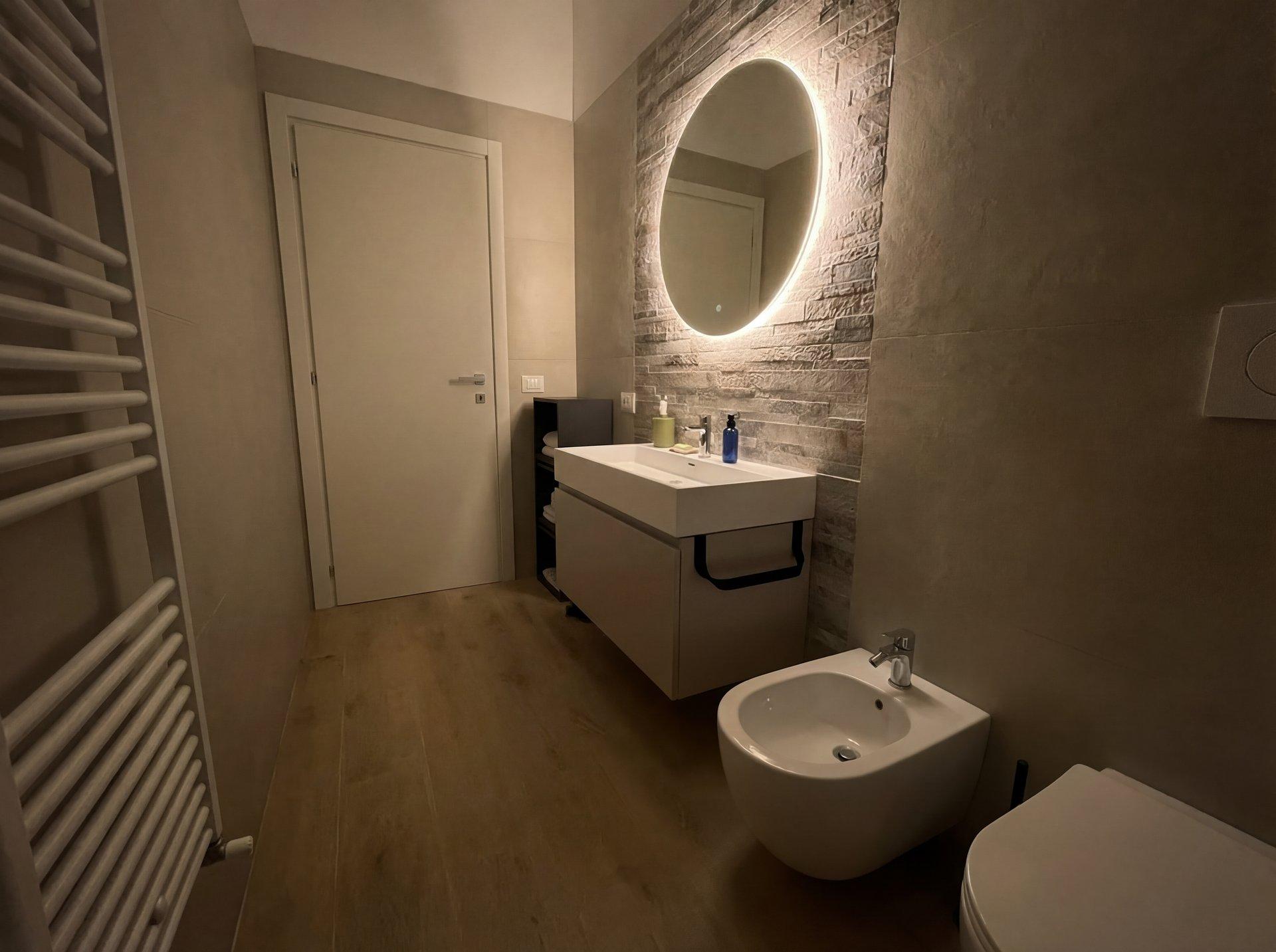 Designer bathroom with walk-in shower, natural stone tiles, and heated towel rail in Terra apartment