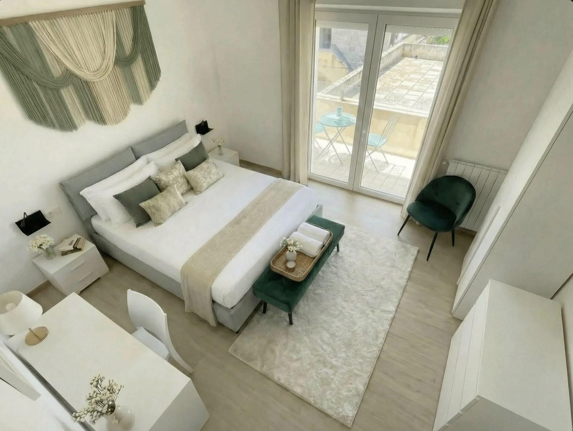 Aerial view of Terra bedroom showing queen bed, teal velvet bench, and balcony access